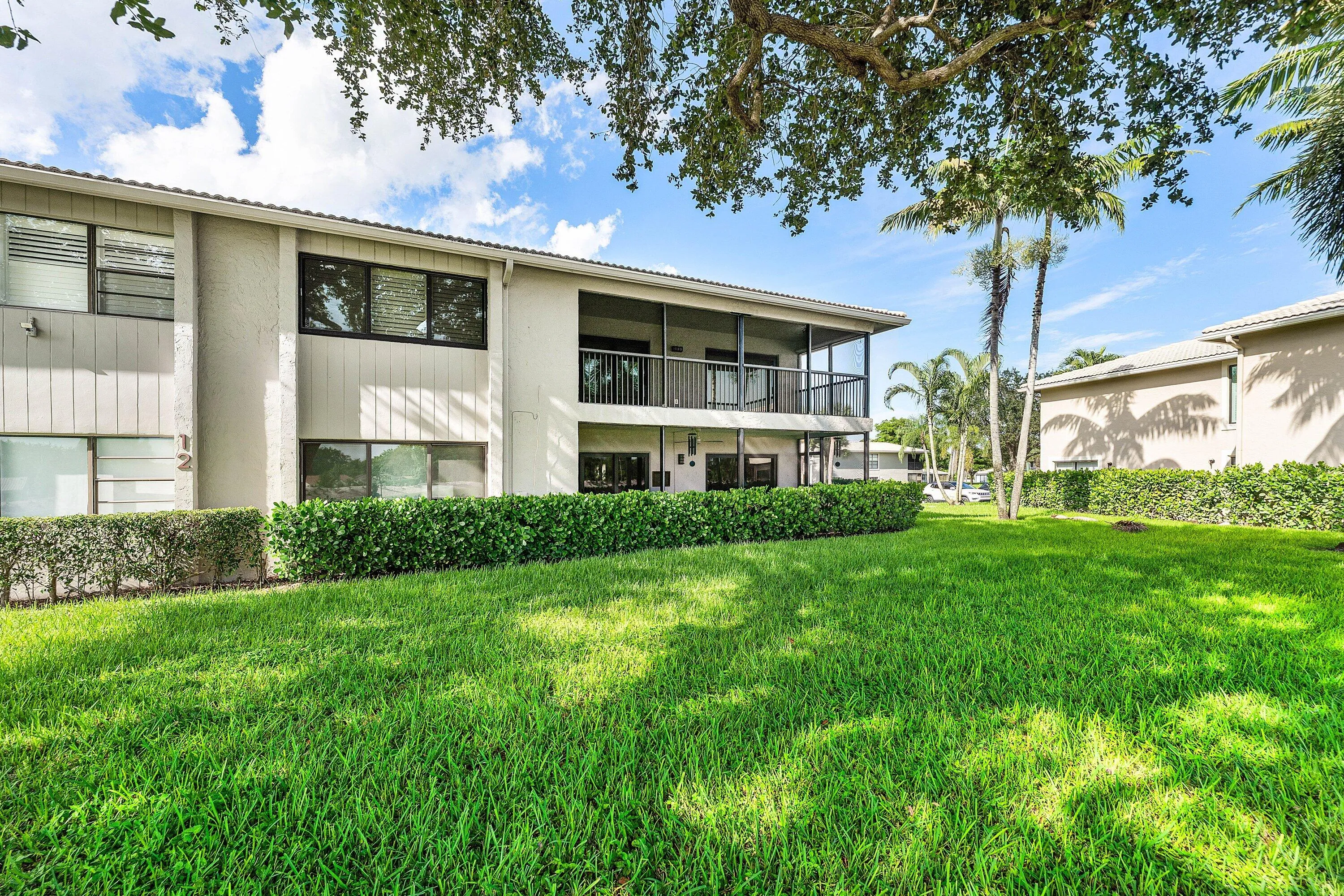 Manicured lawn with dense green hedging and mature trees