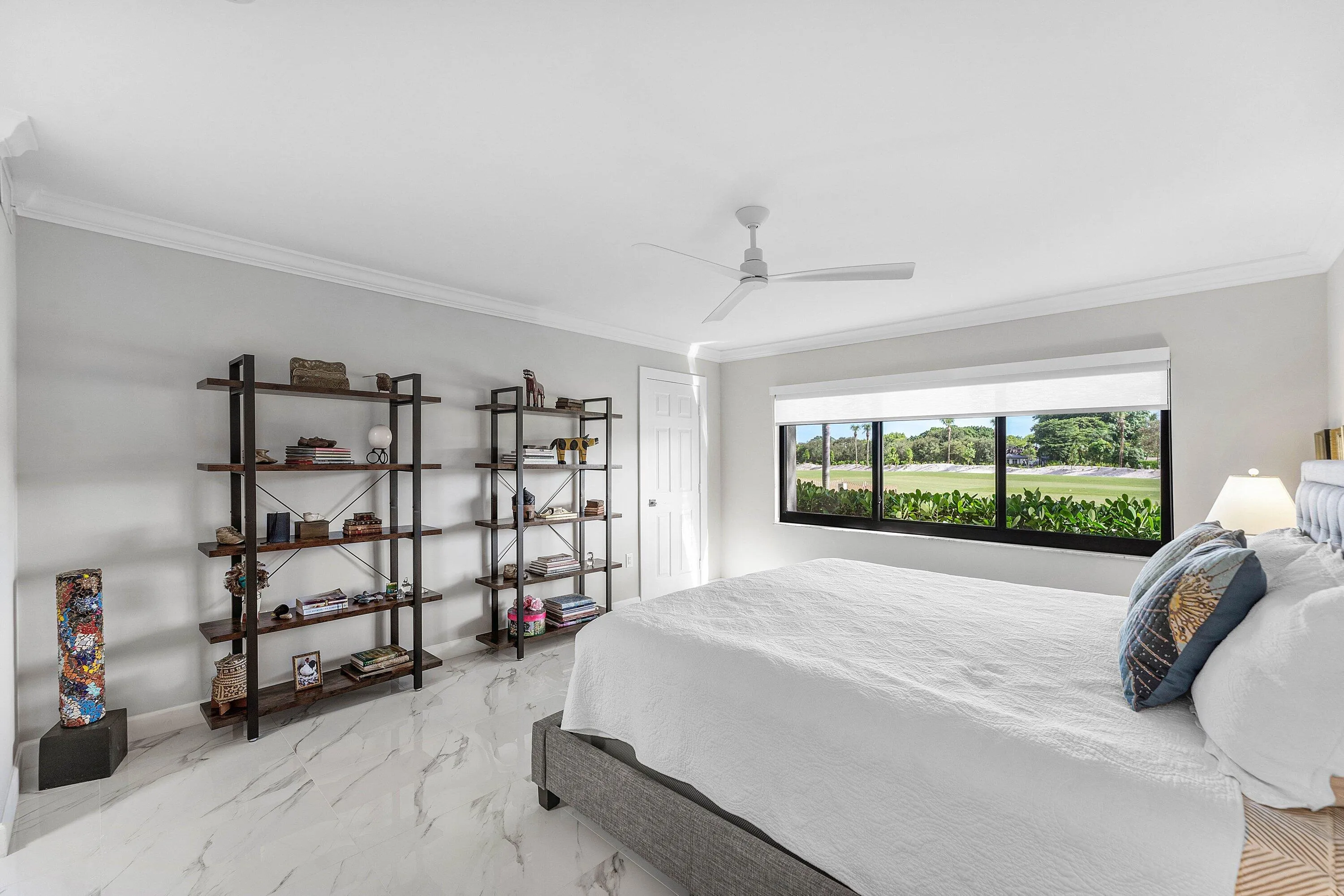 White marble-look flooring, crown molding, a ceiling fan, and a wide window with exterior landscaping