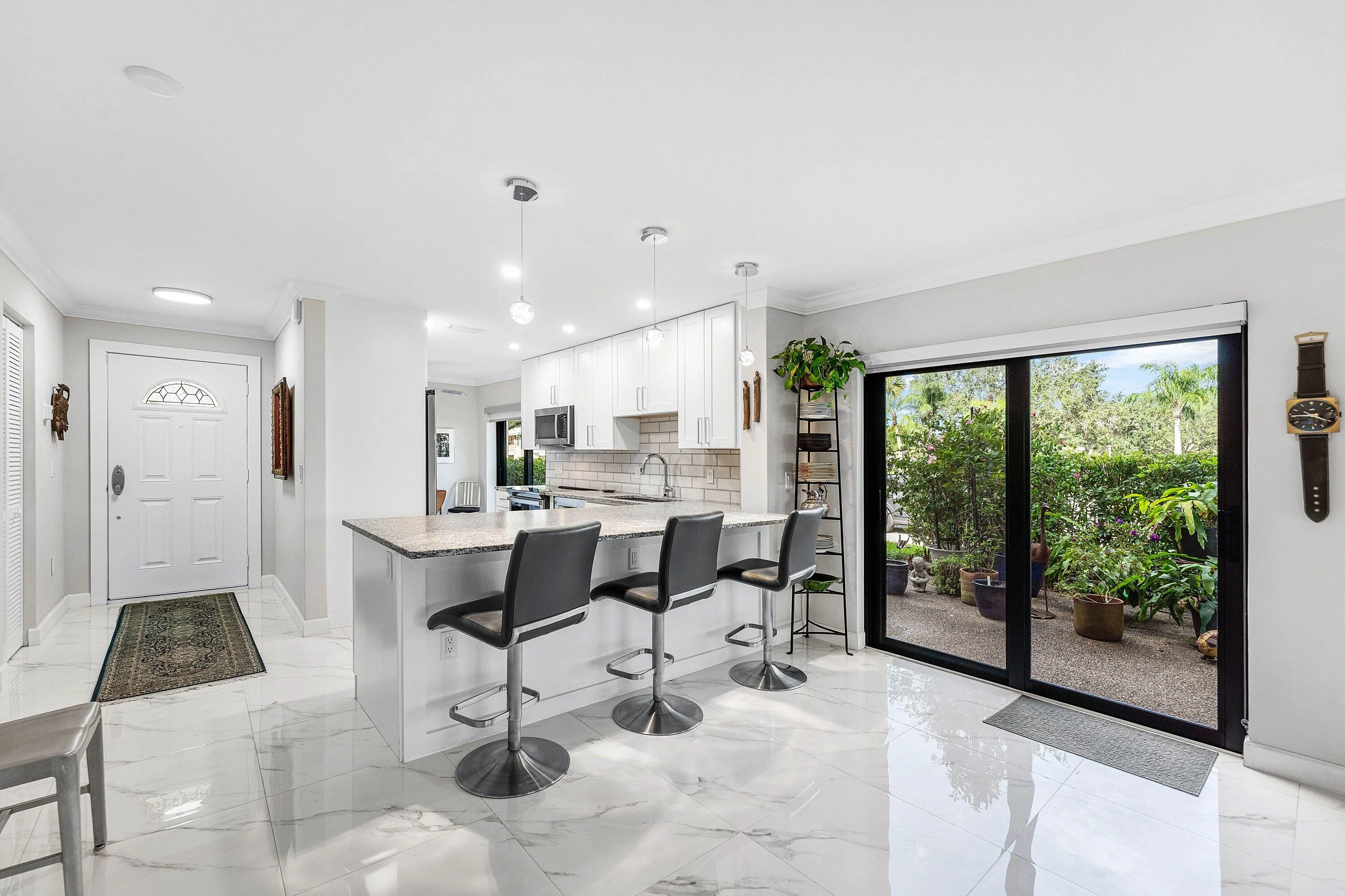 Gleaming white tile flooring, kitchen island with seating, pendant lighting, built-in cabinetry, and sliding glass doors to outdoor space