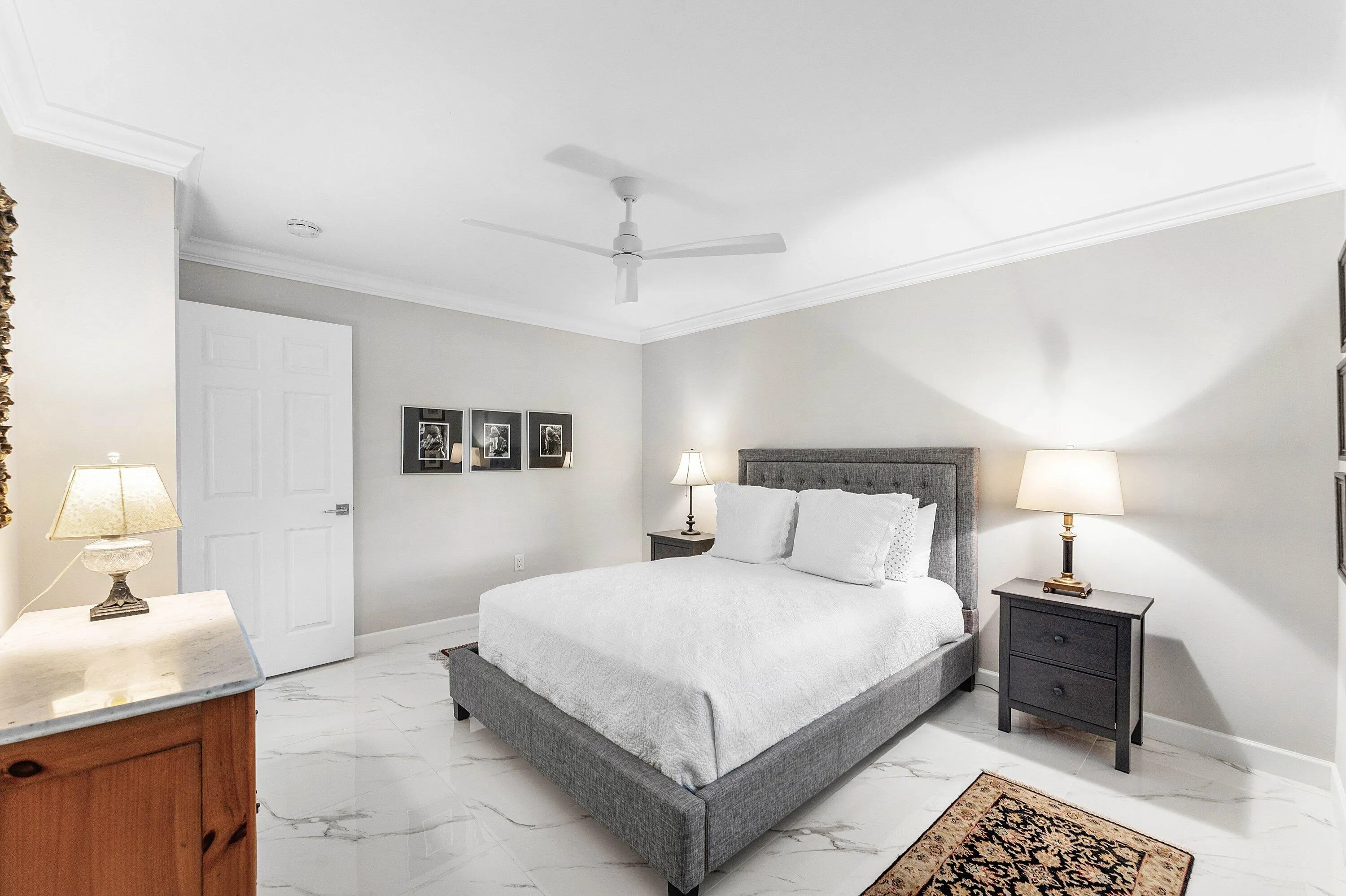 White paneled door, crown molding, ceiling fan, and white tile flooring