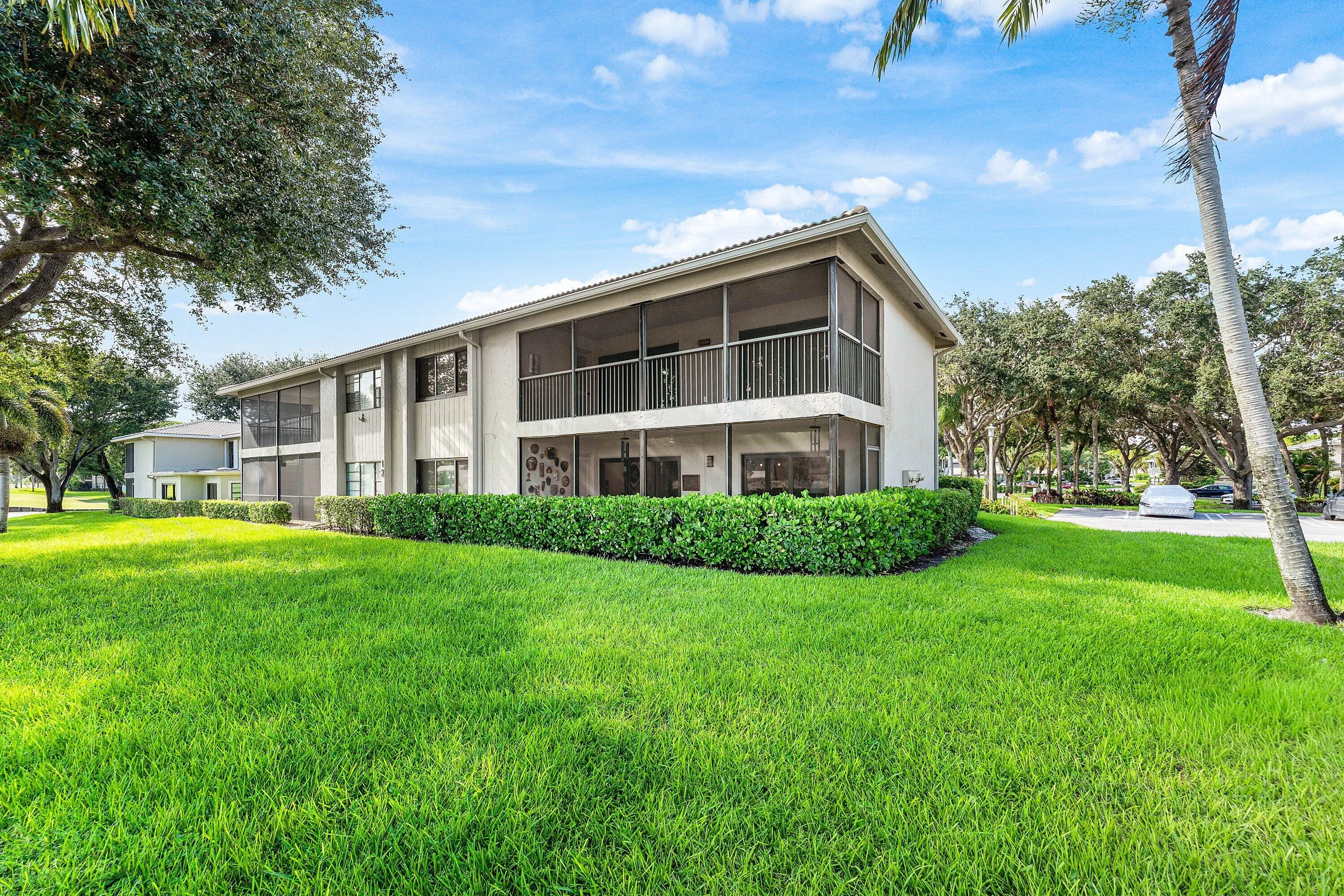 Two-story exterior with screened-in upper balcony, screened-in lower patio, and manicured shrubbery