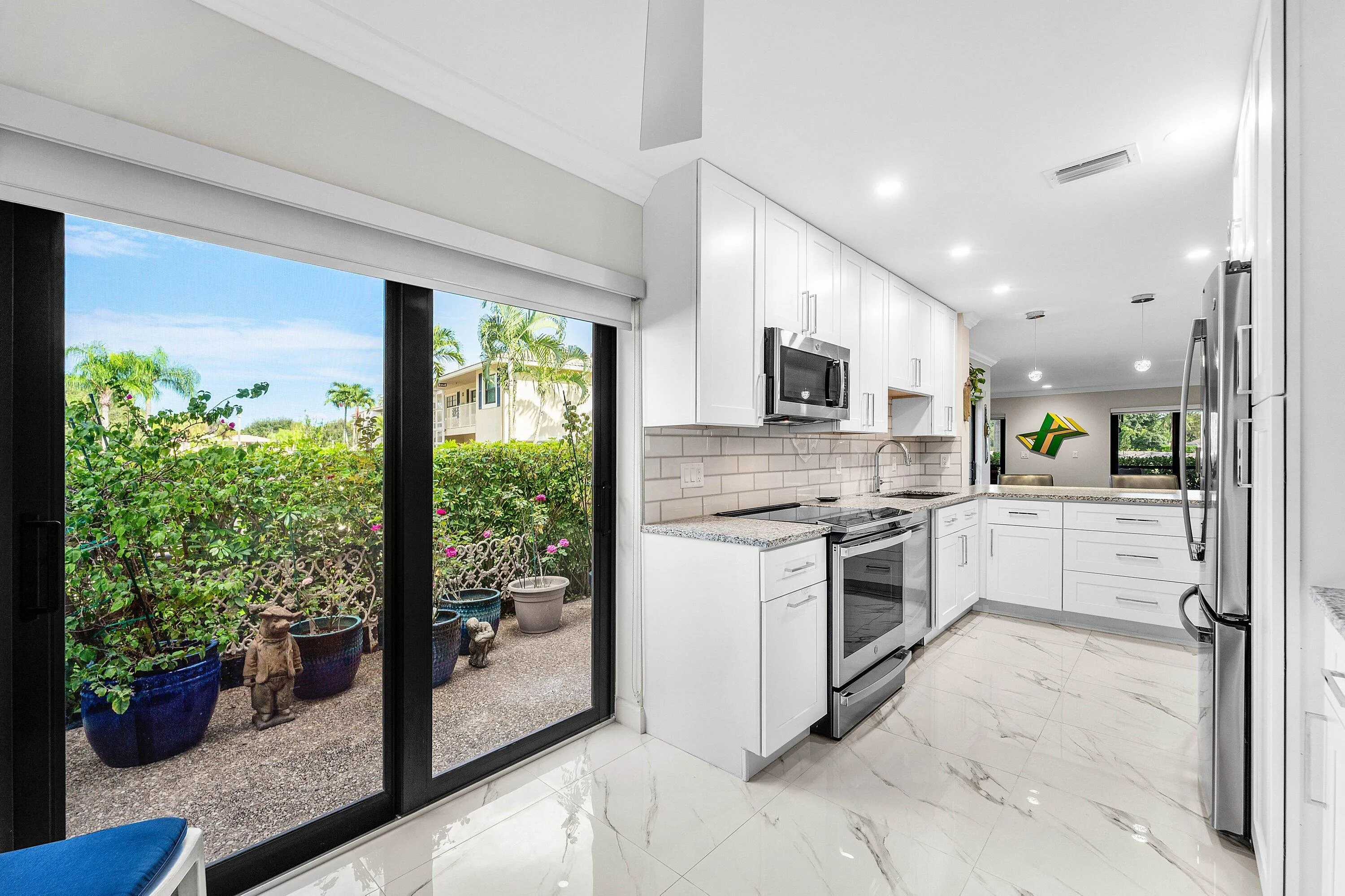 Modern kitchen featuring white cabinetry, stainless steel appliances, light-toned granite countertops, and a subway tile backsplash