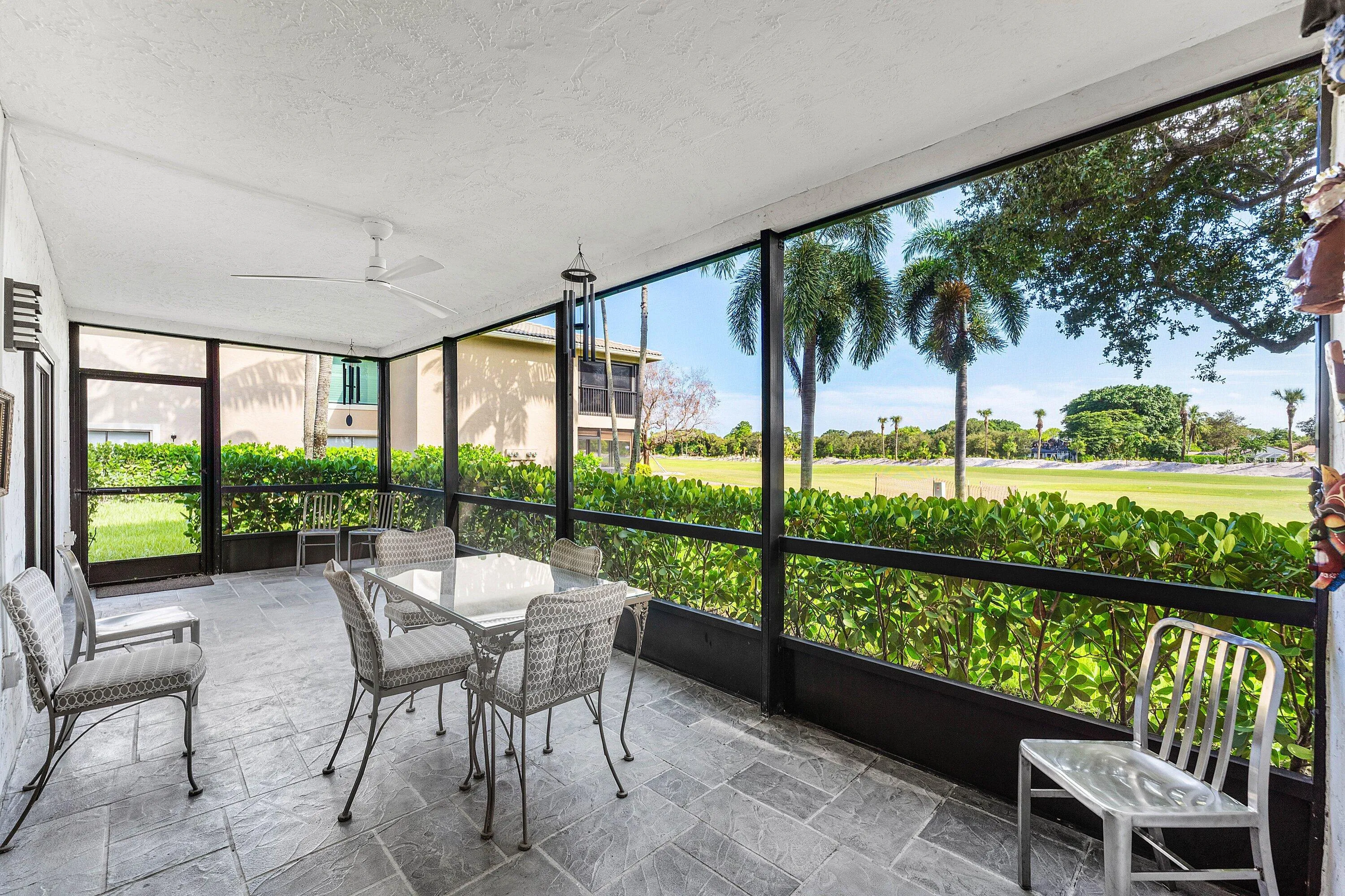 Screened outdoor living area with a ceiling fan, stone tile flooring, and direct access to outdoor greenspace