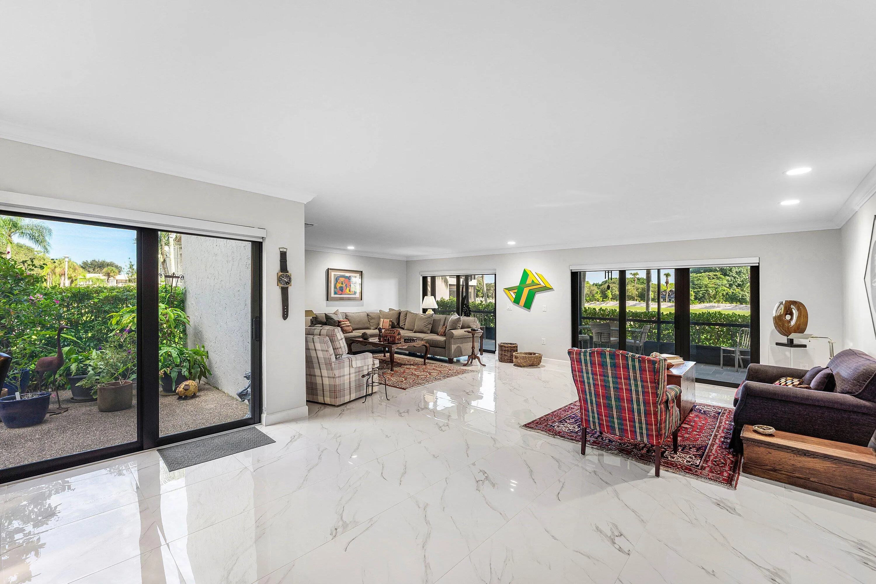 Expansive living area featuring white marble-look tile flooring, recessed lighting, and crown molding