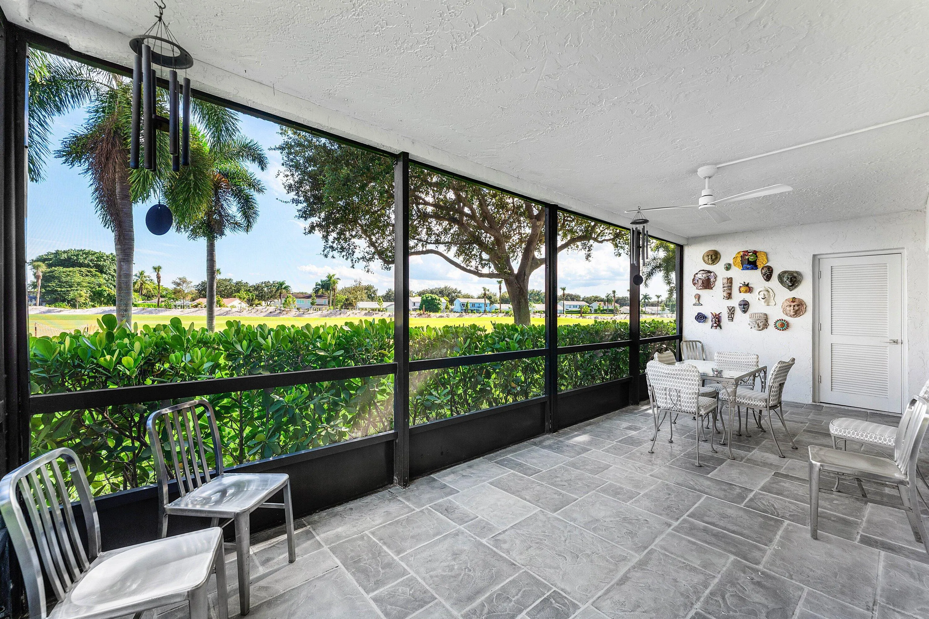 Enclosed screened patio featuring large format tile flooring, a textured ceiling, and a ceiling fan