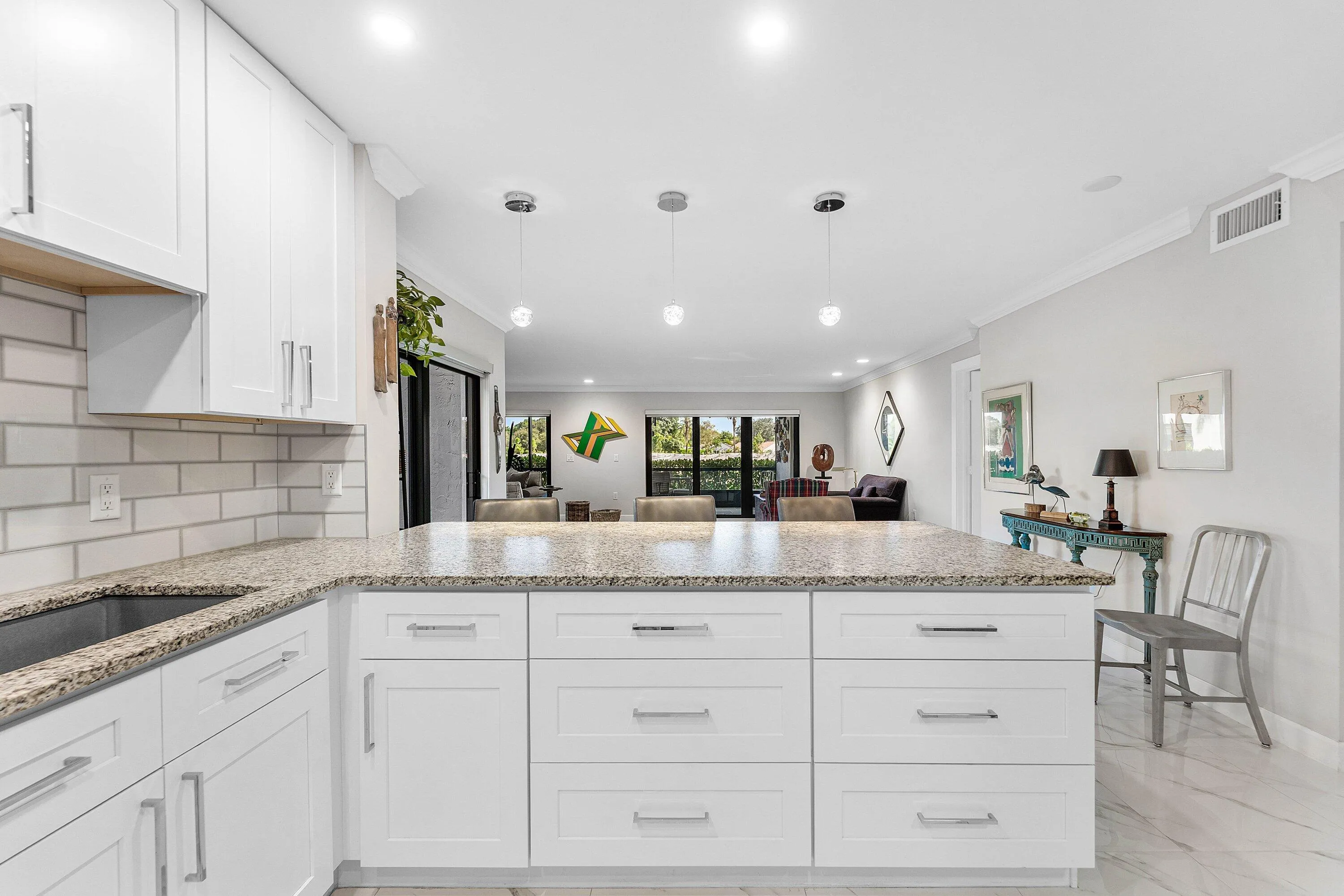 Kitchen featuring white shaker cabinetry, speckled countertops, subway tile backsplash, recessed lighting, and a kitchen island with pendant lighting