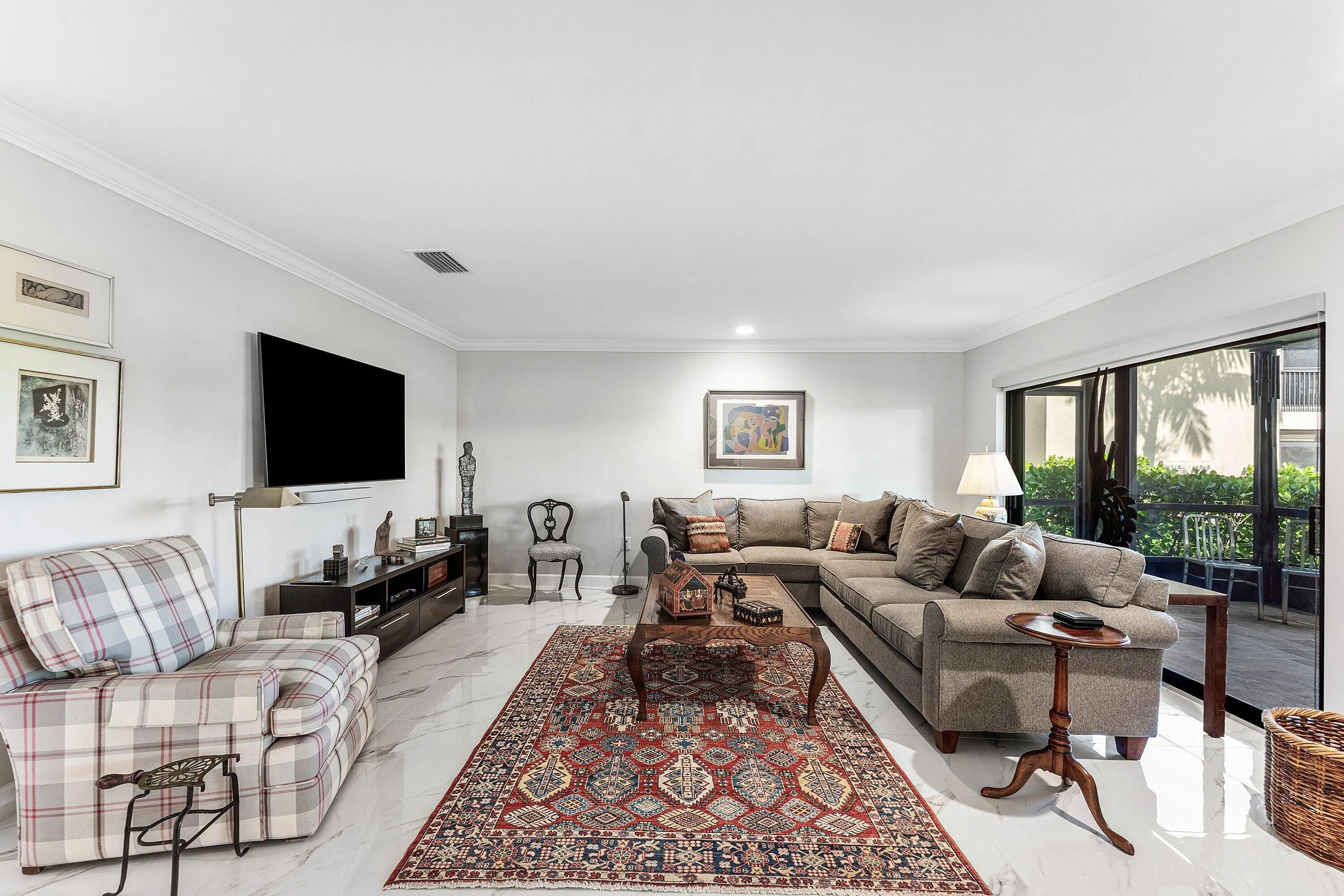 Spacious living area featuring white tile flooring, crown molding, and sliding glass doors