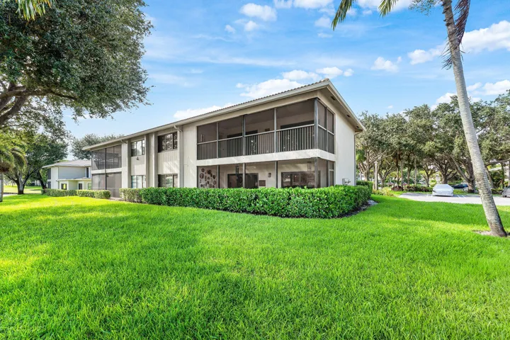Two-story exterior with screened-in upper balcony, screened-in lower patio, and manicured shrubbery