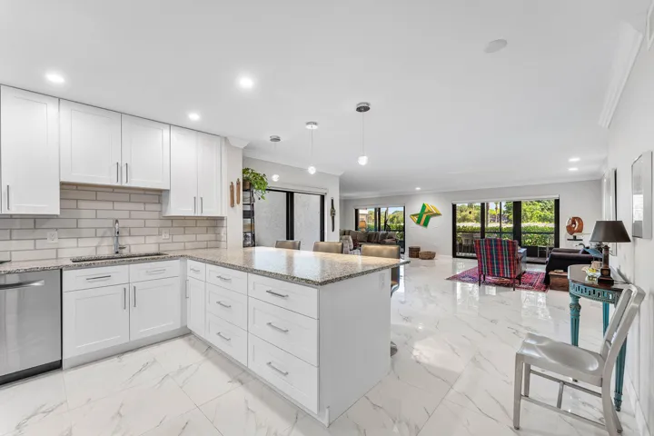 Updated kitchen featuring white shaker cabinetry, stainless steel dishwasher, and a center island with pendant lighting