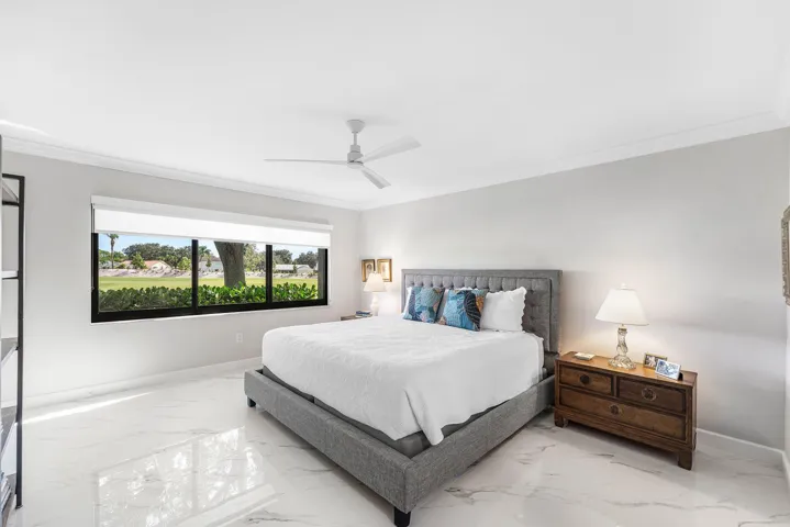 White tile flooring, expansive window with exterior scenery, crown molding, and a ceiling fan