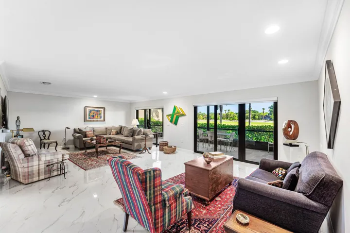 White tile flooring, recessed lighting, crown molding, and glass sliding doors leading to an outdoor patio with a concrete surface