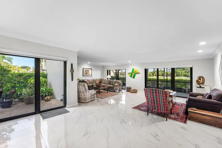 Expansive living area featuring white marble-look tile flooring, recessed lighting, and crown molding