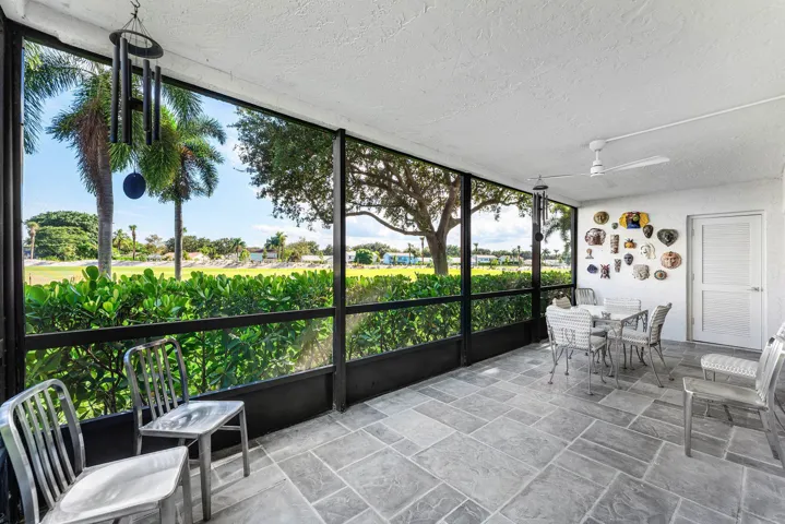 Enclosed screened patio featuring large format tile flooring, a textured ceiling, and a ceiling fan