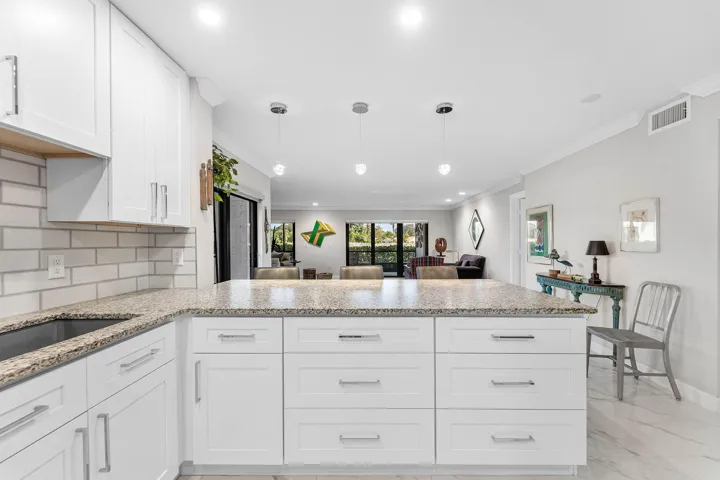 Kitchen featuring white shaker cabinetry, speckled countertops, subway tile backsplash, recessed lighting, and a kitchen island with pendant lighting
