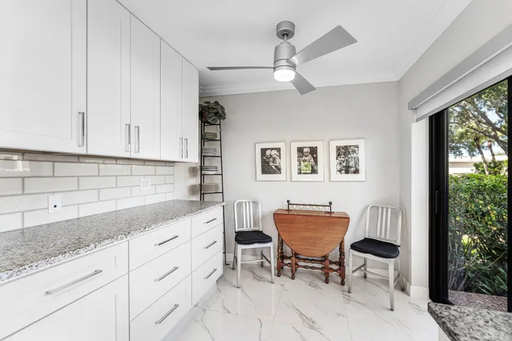 White shaker cabinetry with brushed nickel hardware, light-toned granite-finish countertops, white subway tile backsplash, and large-format porcelain tile flooring