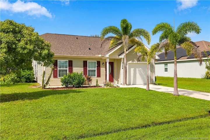 Single-story home with light exterior, covered entry, and mature landscaping