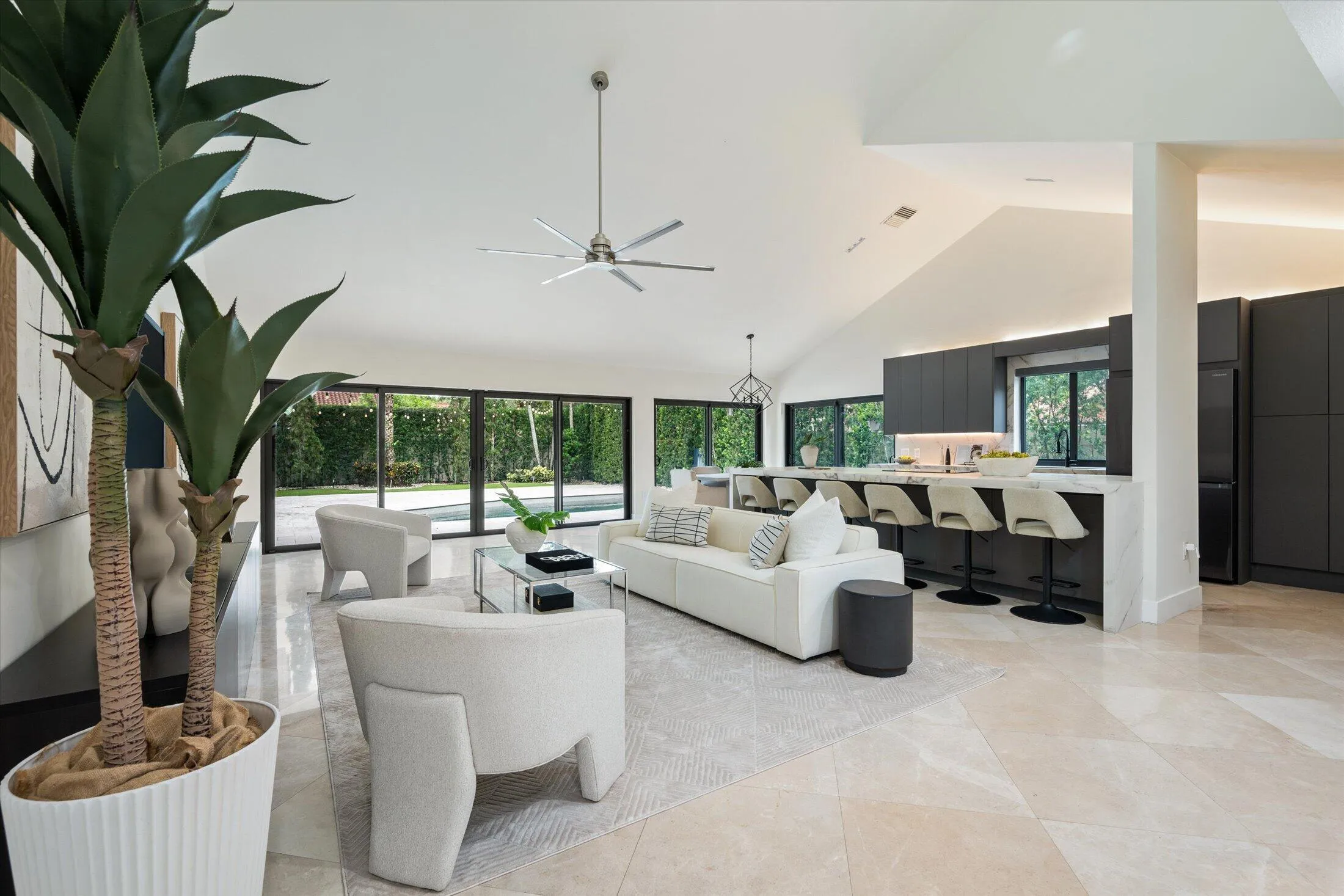 Vaulted ceilings, large format tile flooring, built-in kitchen cabinetry, and expansive glass doors