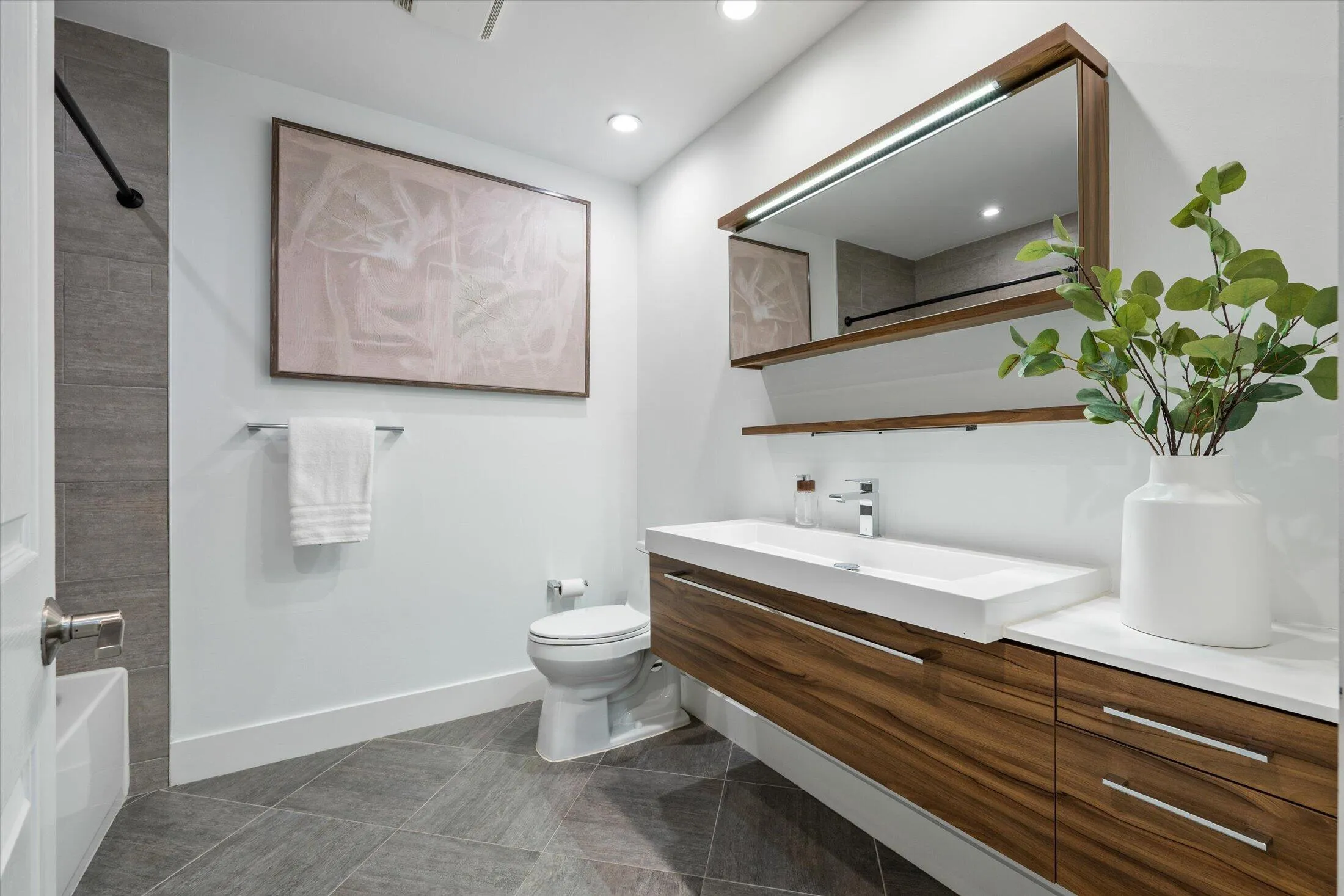 Integrated vanity with wood-finish cabinetry, white countertop, and rectangular undermount sink