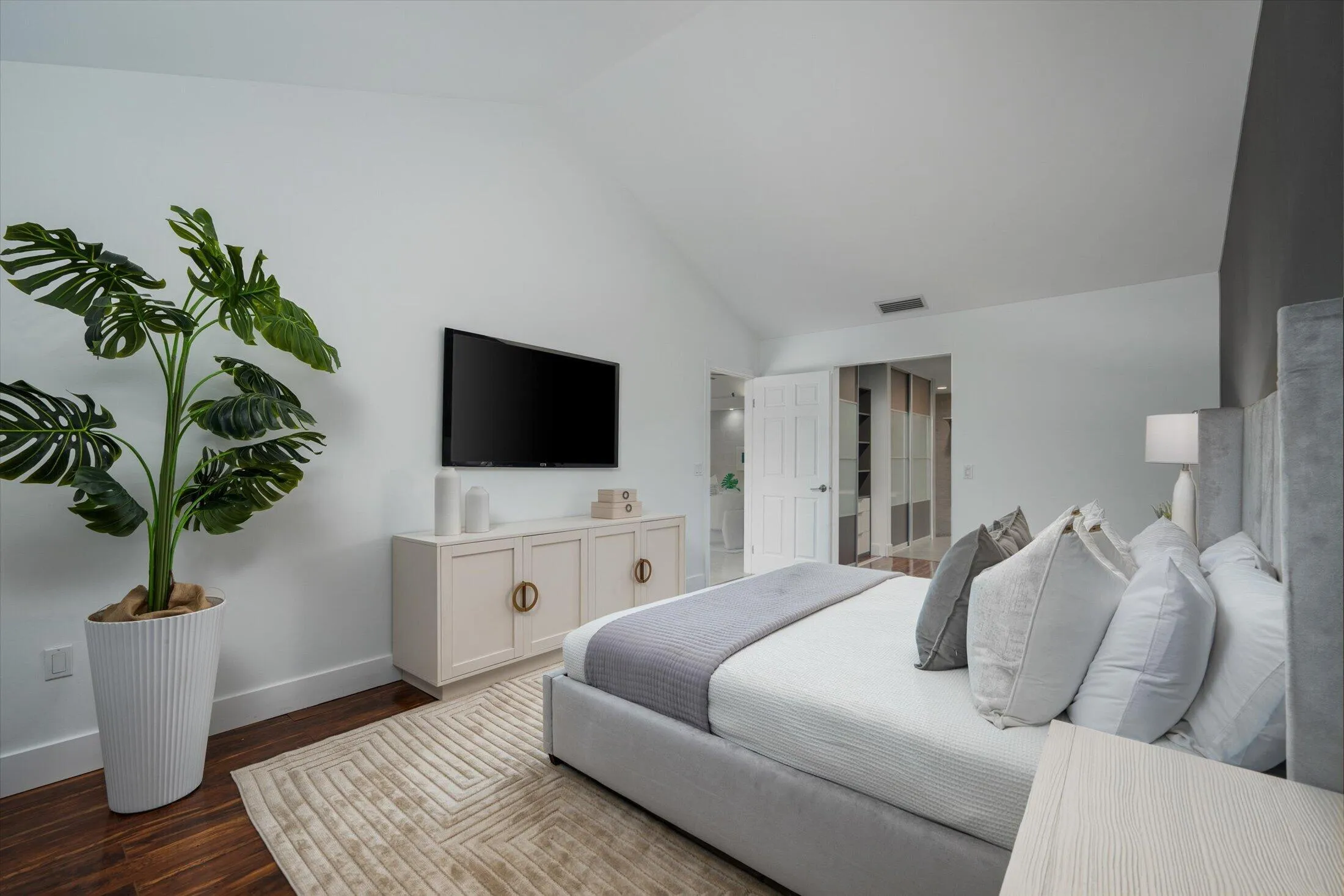 Vaulted ceiling accentuates the spacious room, complemented by wood-finish flooring and a white paneled door