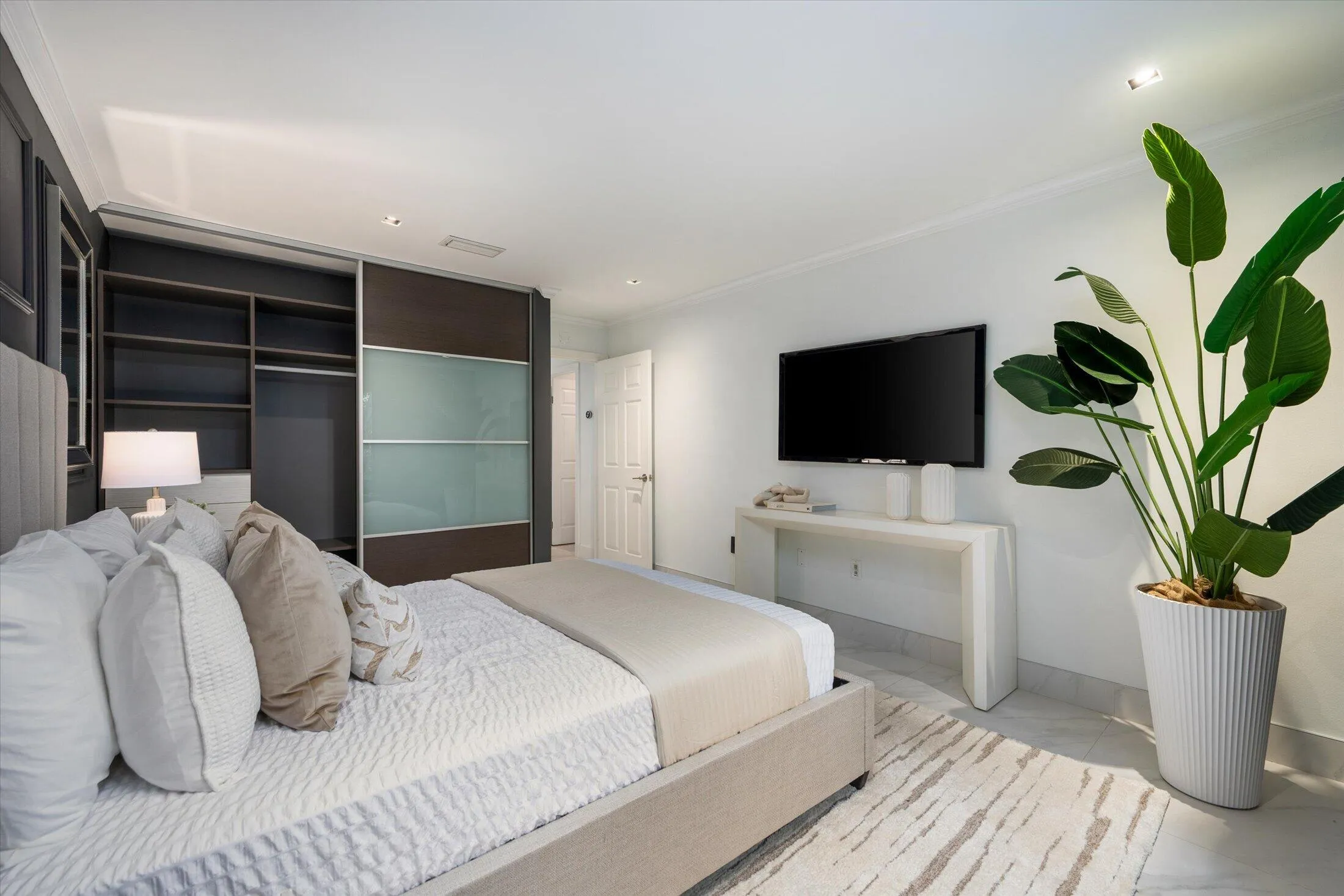 Built-in closet with sliding doors, recessed lighting, white walls, light-toned flooring, and crown molding