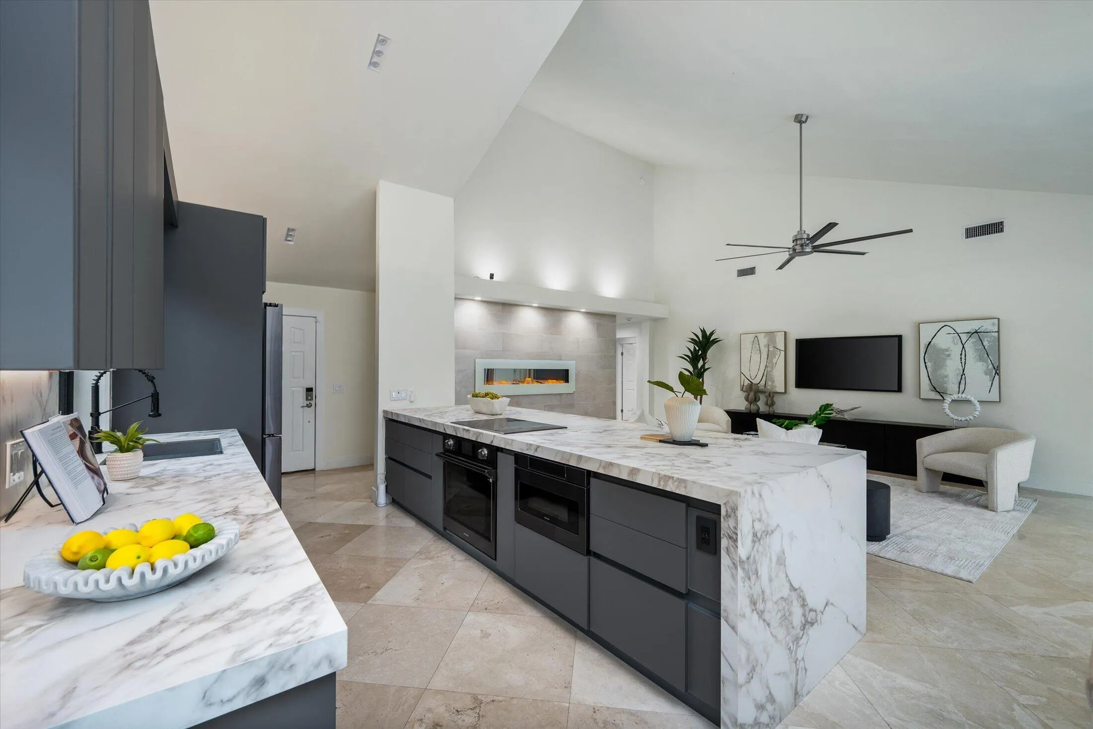Spacious living area featuring vaulted ceilings, a modern ceiling fan, and light-toned tile flooring
