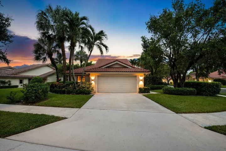 Mediterranean-style exterior featuring a tile roof, an integrated two-car garage, manicured landscaping, and a concrete driveway