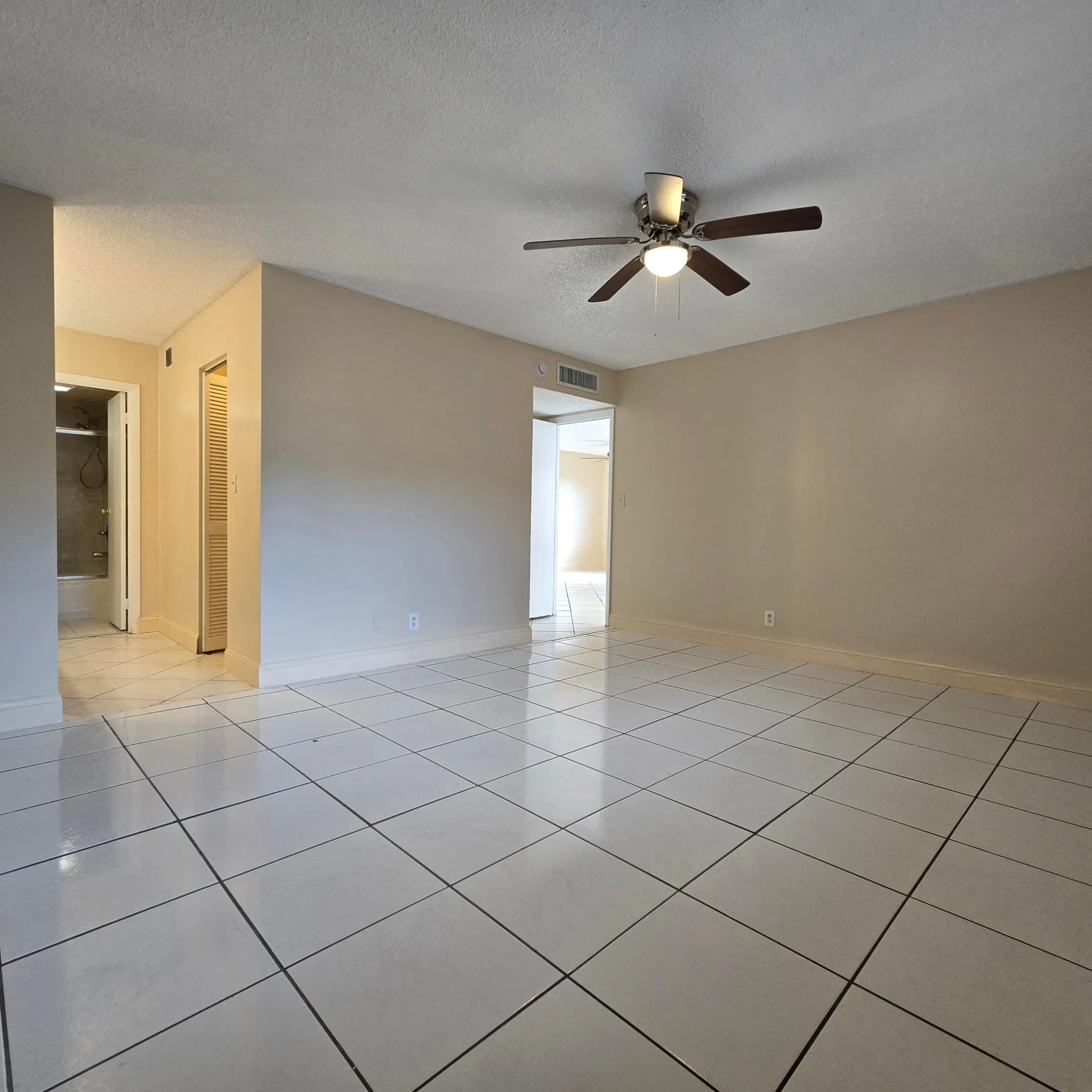 White square tile flooring, neutral paint and a ceiling fan with integrated lighting.