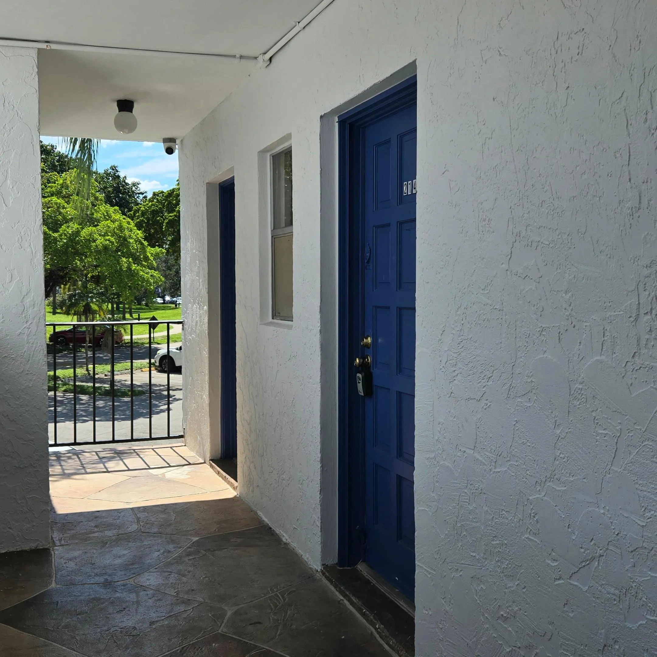 Textured exterior white walls with a bold blue panel door