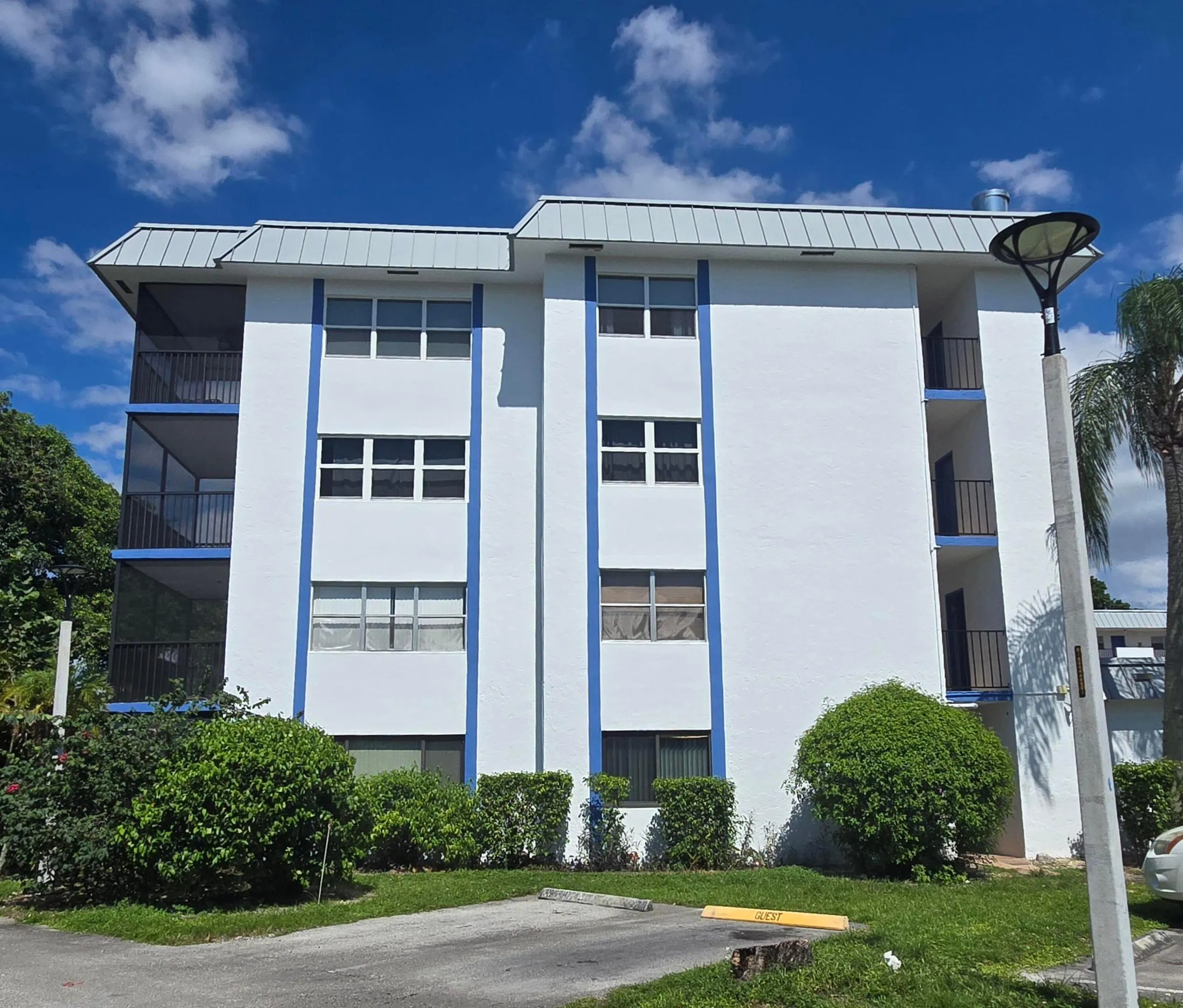 Multi-story building featuring a light-colored exterior with blue accents and multiple screened balconies