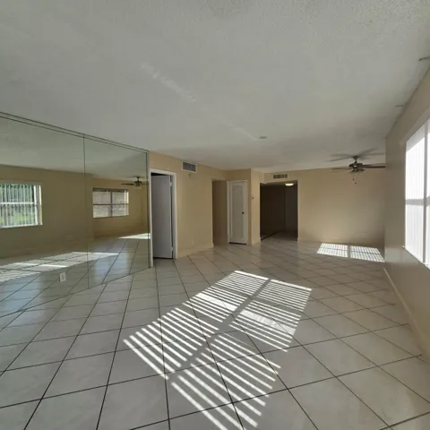 Tile flooring, mirrored wall, multiple windows and a ceiling fan.