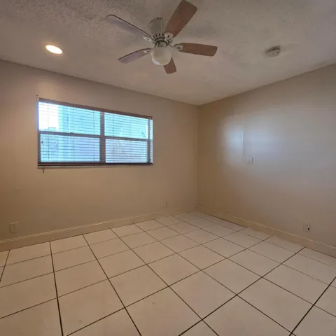 Recessed ceiling lighting, ceiling fan with light fixture, window with blinds, tile flooring, and neutral paint.