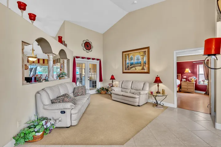 Vaulted ceiling, arched architectural feature, French doors with transom windows, tile flooring, and carpeted area
