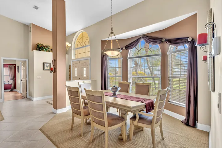 Arched windows with horizontal blinds, a decorative light fixture, and tile flooring