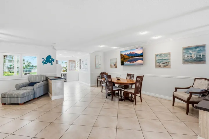 Recessed lighting illuminates the space, featuring large square floor tiles and multiple windows