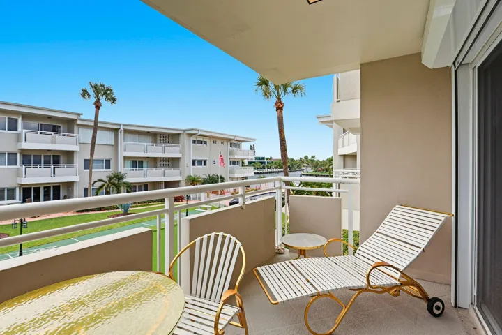 Private balcony with a smooth concrete floor, white metal railing, and a sliding glass door