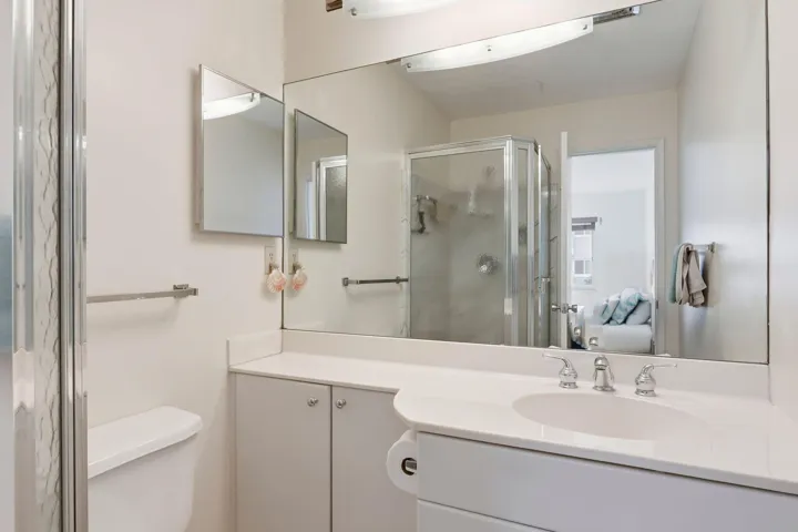 White vanity with integrated sink, chrome faucet, and expansive wall-mounted mirror