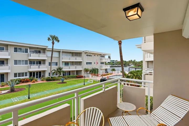 Balcony with white metal railing, overhead light fixture, and water frontage