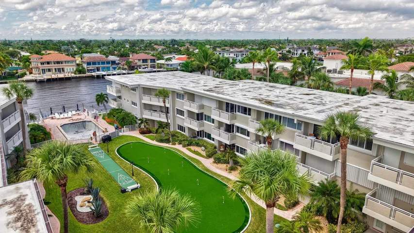 Waterfront condominium complex featuring multiple balconies, a putting green, a shuffleboard court, and an in-ground swimming pool