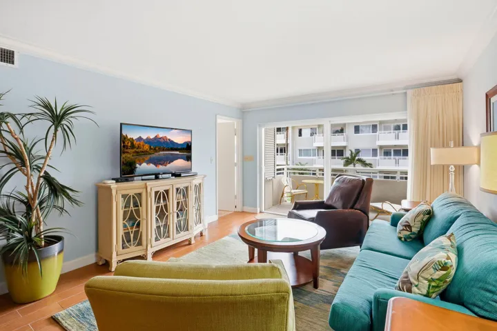 Light-toned wood-finish flooring, light blue wall paint, crown molding, and a sliding glass door to a balcony