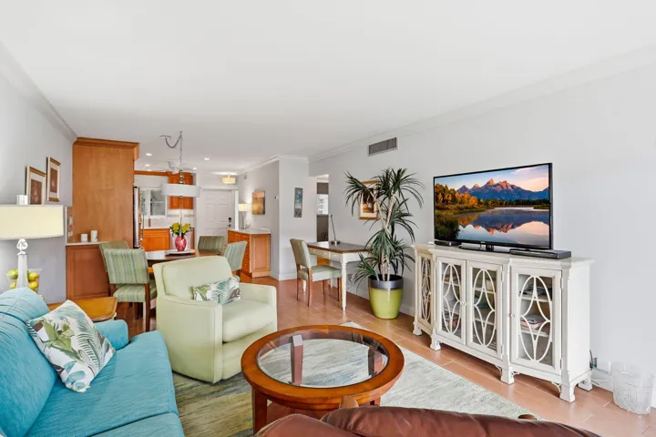 Open-concept living space with light-toned walls, crown molding, and wood-finish flooring