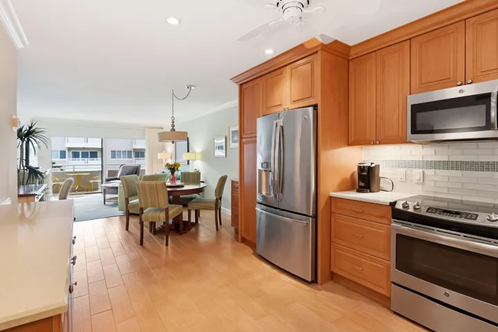 Kitchen featuring stainless steel appliances, wood-finish cabinetry, light countertops, and subway tile backsplash