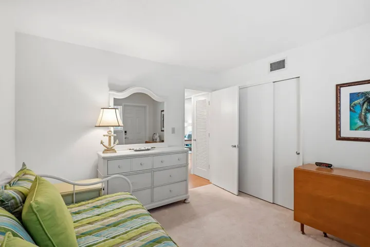 White wall finishes, carpeted flooring, and a mirrored dresser