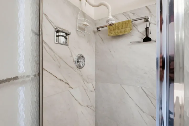 Shower enclosure featuring marble-look wall tiling and a chrome shower fixture