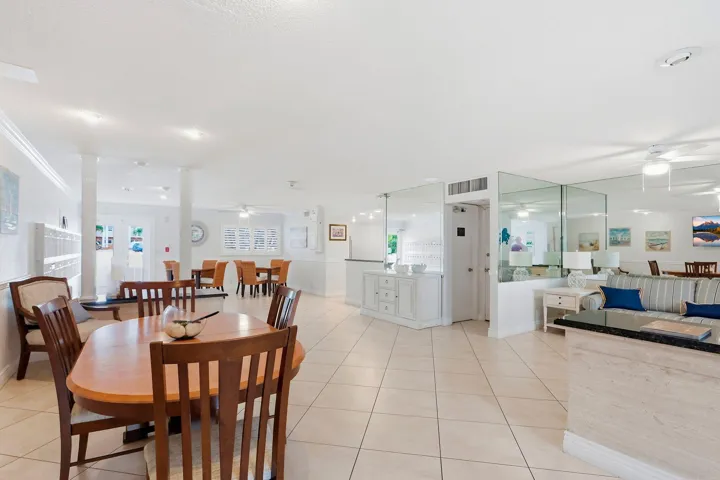 Open-concept interior featuring large format tile flooring, crown molding, multiple columns, and mirrored wall accents