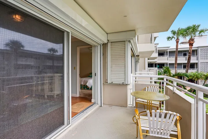 Balcony with a concrete surface, white railings, and a sliding glass door
