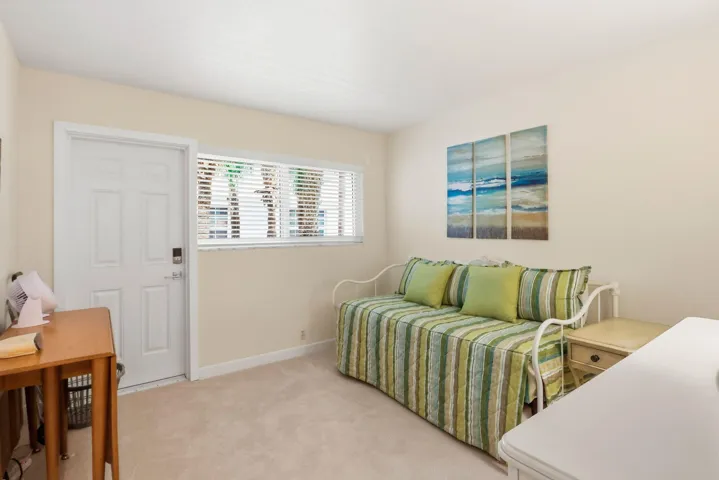 Carpeted room with a white paneled door, horizontal window with blinds, and neutral wall paint