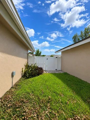 Sunny Stucco Side Yard with White Gate