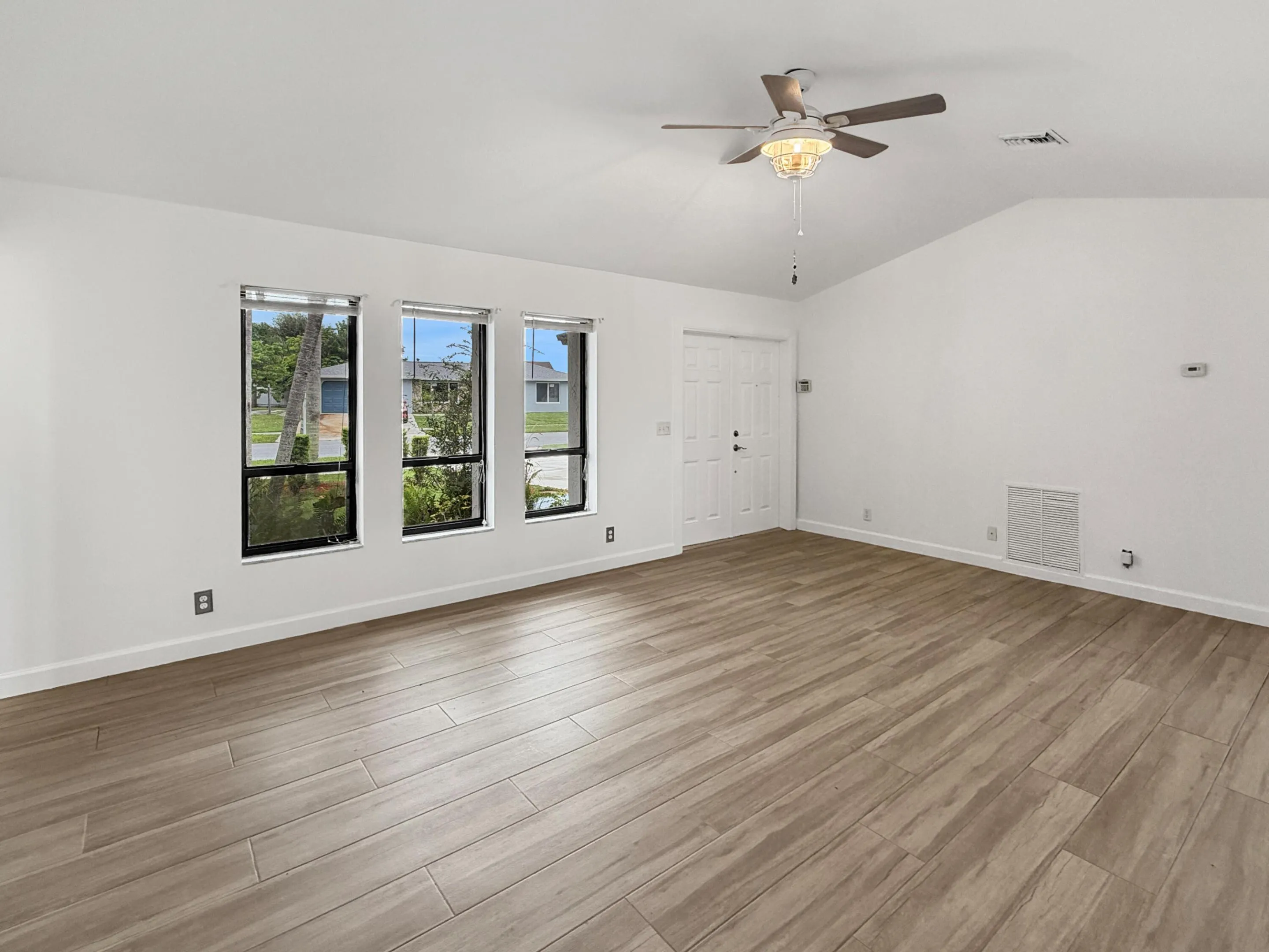 Vaulted ceilings, wood-finish flooring, three large windows, and a ceiling fan with light​​‌​​​​‌​​‌‌​‌‌​​​‌‌​‌​‌​‌​​​‌​​ fixture