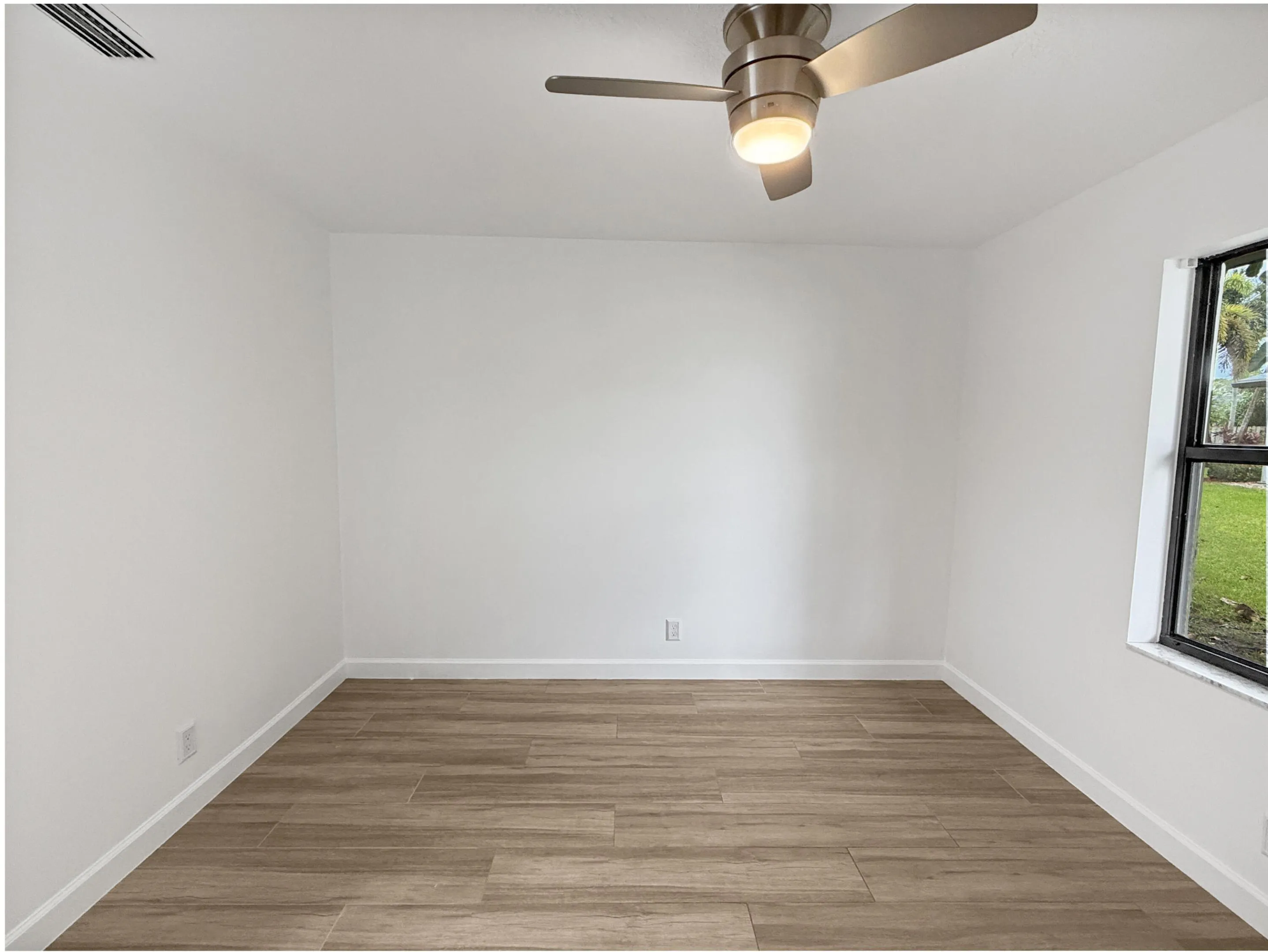 Wood-finish tile flooring, white painted walls, and a ceiling fan with integrated lighting