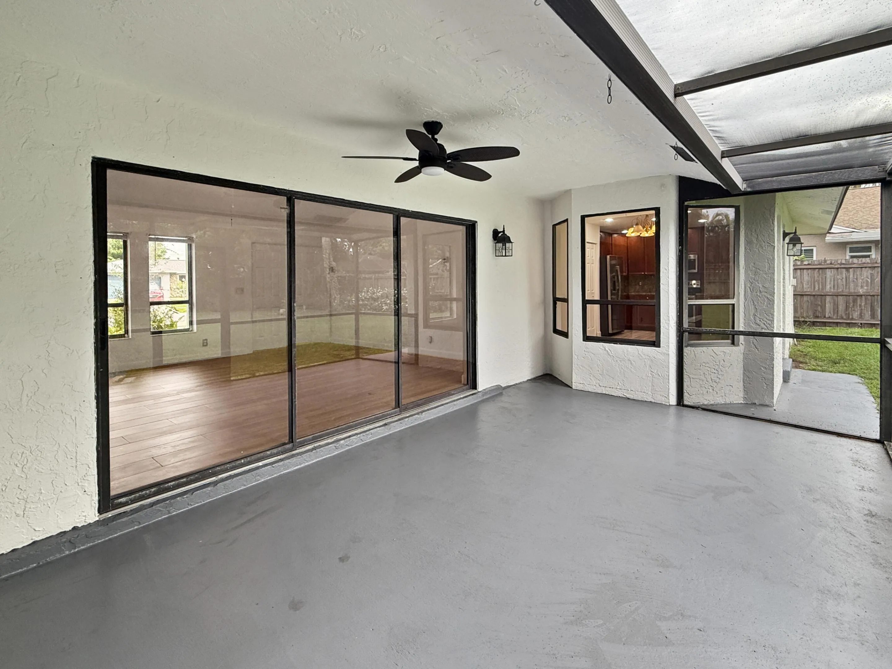Screened patio featuring a ceiling fan, painted concrete flooring, and exterior wall sconces